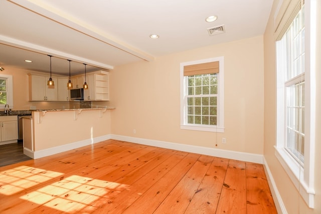 interior space featuring kitchen peninsula, a healthy amount of sunlight, decorative light fixtures, and a kitchen bar