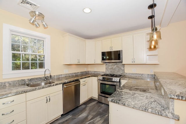 kitchen with kitchen peninsula, dark hardwood / wood-style floors, stainless steel appliances, sink, and decorative light fixtures