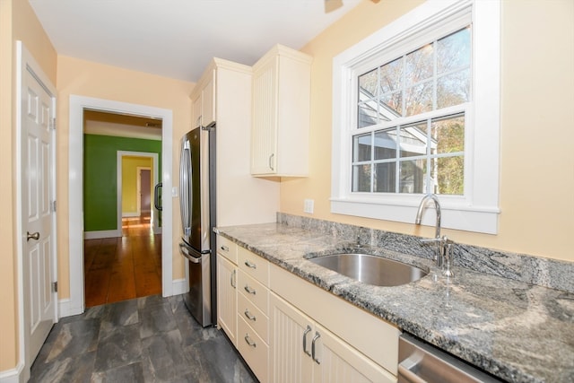 kitchen with cream cabinetry, sink, stone countertops, and stainless steel appliances