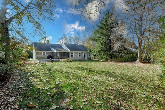 back of property featuring a patio, a sunroom, and a lawn