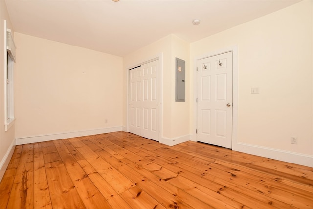 spare room featuring electric panel and light wood-type flooring