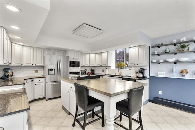 23 Mulholland Dr, Ipswich, MA 01938 - kitchen with stainless steel appliances, light flooring, a kitchen island, a breakfast bar, and decorative backsplash
