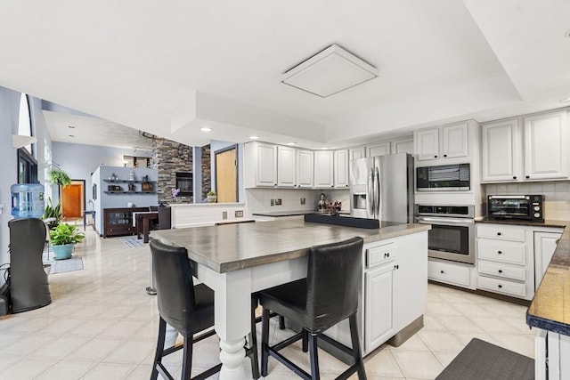 23 Mulholland Dr, Ipswich, MA 01938 - kitchen with stainless steel appliances, tasteful backsplash, dark countertops, a kitchen bar, and a kitchen island