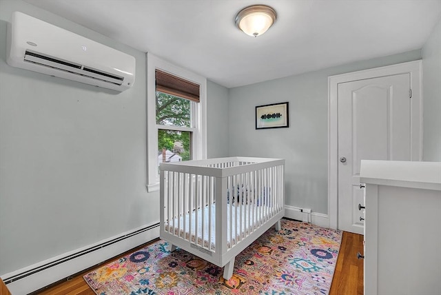 72 Marlboro St, Dedham, MA 02026 - bedroom featuring a wall mounted air conditioner, a baseboard radiator, wood finished floors, and a nursery area