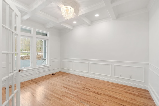 empty room featuring a notable chandelier, beamed ceiling, hardwood / wood-style flooring, and coffered ceiling