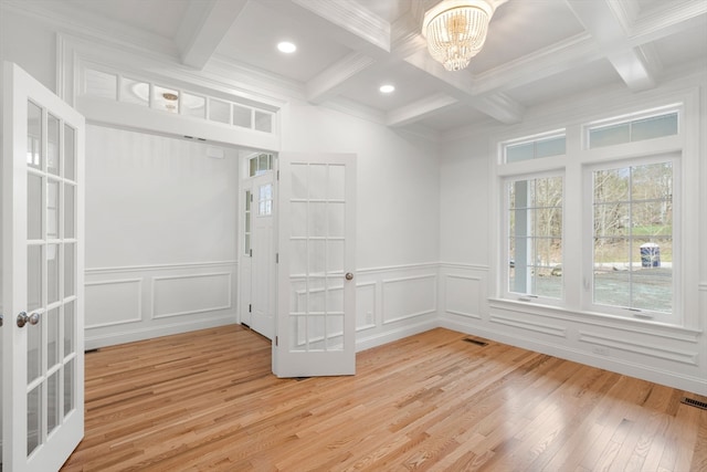 empty room featuring beamed ceiling, coffered ceiling, light hardwood / wood-style flooring, and a notable chandelier