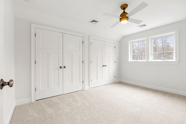 unfurnished bedroom featuring lofted ceiling, multiple closets, ceiling fan, and carpet flooring