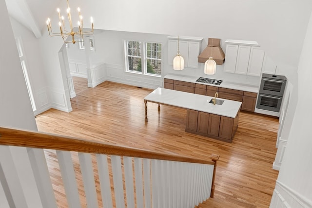 interior space with light wood-type flooring, a chandelier, and a high ceiling