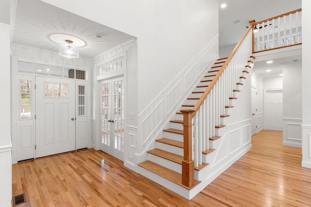 entrance foyer featuring light hardwood / wood-style floors, ornamental molding, and french doors