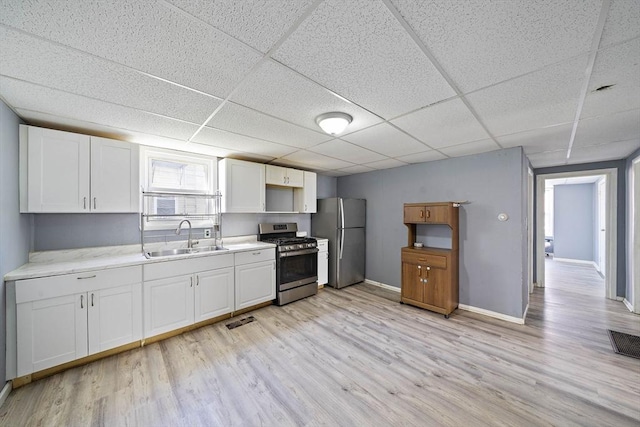48 Rocliffe St, Fall River, MA 02723 - kitchen featuring stainless steel appliances, a sink, light wood-style flooring, a drop ceiling, and white cabinetry