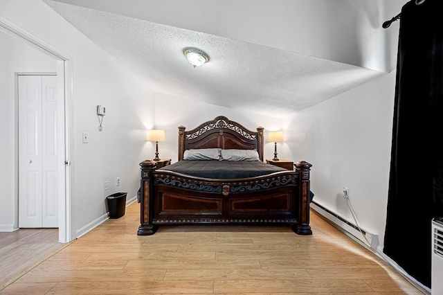 98 Eastern Ave Unit 403, Worcester, MA 01605 - bedroom with a baseboard heating unit, a textured ceiling, light wood-style floors, vaulted ceiling, and baseboards