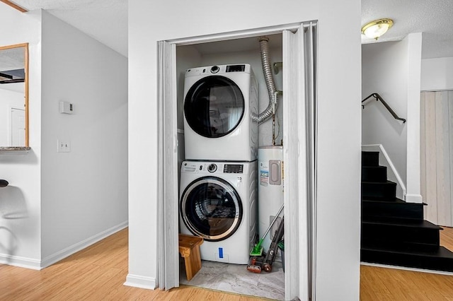 98 Eastern Ave Unit 403, Worcester, MA 01605 - washroom featuring stacked washing machine and dryer, electric water heater, wood finished floors, and baseboards