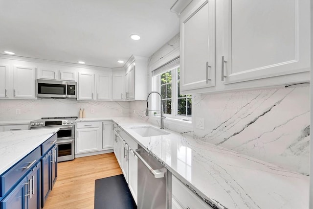 47 Fenwick Cir, Methuen, MA 01844 - kitchen featuring blue cabinetry, appliances with stainless steel finishes, white cabinets, light wood finished floors, and recessed lighting