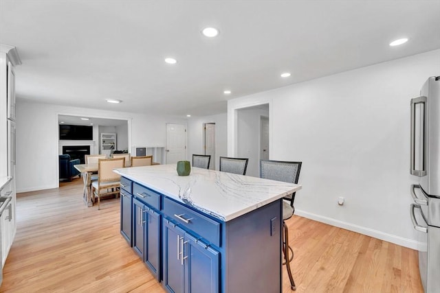47 Fenwick Cir, Methuen, MA 01844 - kitchen featuring freestanding refrigerator, blue cabinets, a kitchen island, light wood finished floors, and a kitchen bar