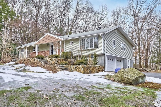 view of front of property featuring a garage, a chimney, and driveway