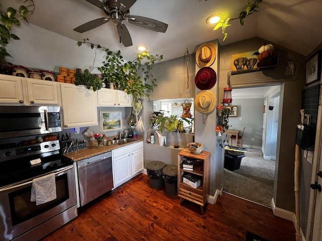 kitchen with vaulted ceiling, dark wood-style floors, white cabinets, stainless steel appliances, and a sink