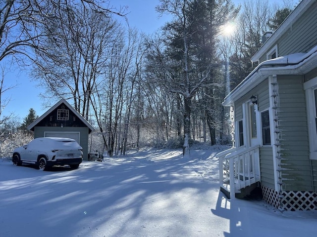 snowy yard with a detached garage and an outbuilding