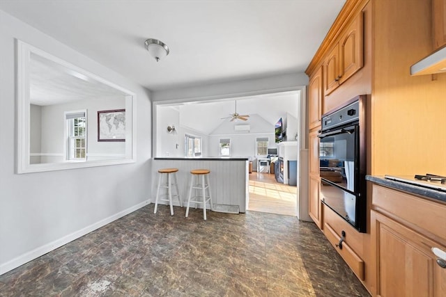 kitchen featuring oven, a kitchen bar, a warming drawer, dark countertops, and baseboards