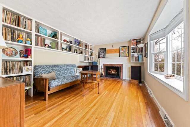 sitting room featuring visible vents, a brick fireplace, baseboards, and hardwood / wood-style floors