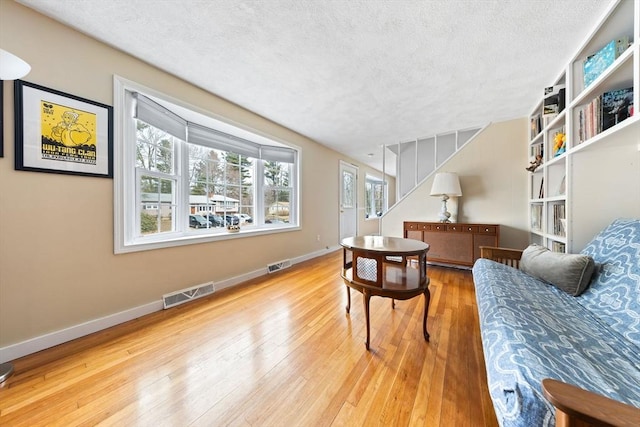 sitting room featuring visible vents, a textured ceiling, and hardwood / wood-style floors