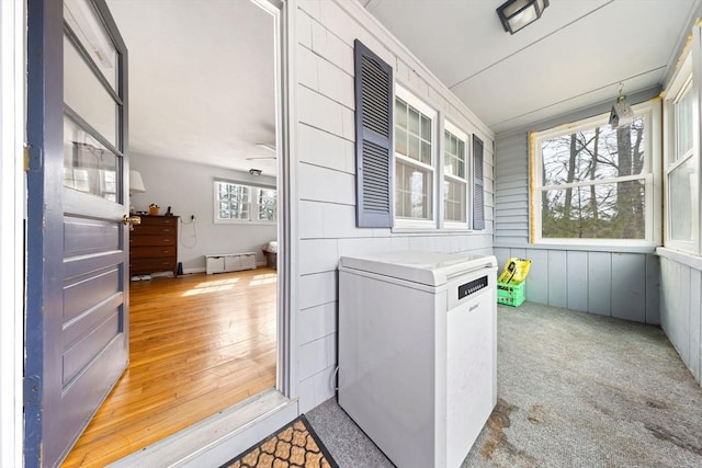 laundry area featuring baseboard heating, wood finished floors, and carpet