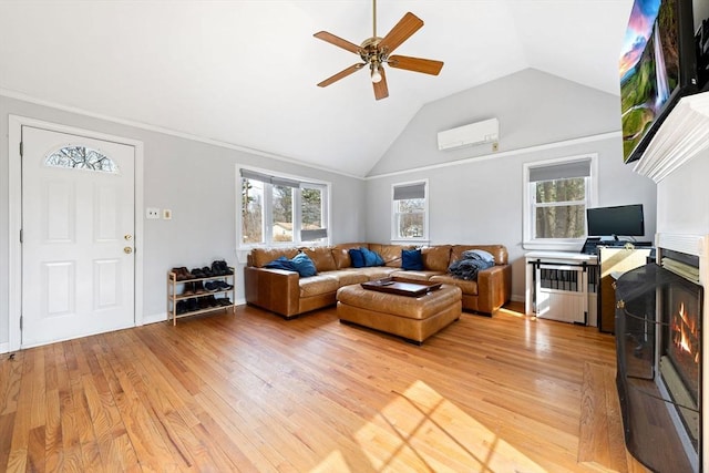 living area with lofted ceiling, a ceiling fan, light wood-style floors, and a wall unit AC