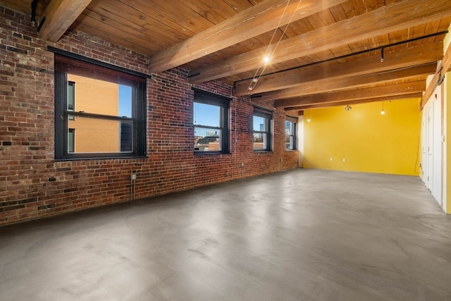 empty room with beam ceiling, concrete flooring, brick wall, and wooden ceiling