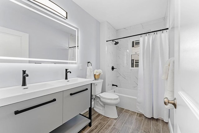 bathroom featuring wood finish floors, a sink, toilet, and double vanity