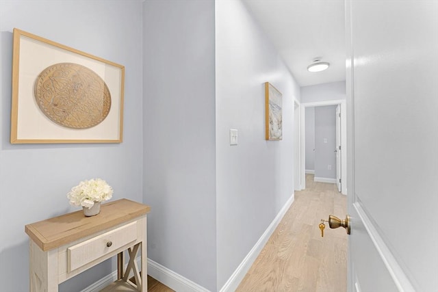 corridor featuring baseboards and wood finished floors