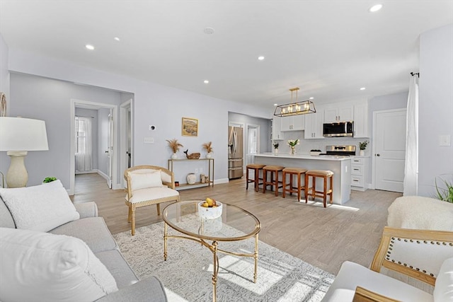 living area with recessed lighting, baseboards, and light wood finished floors