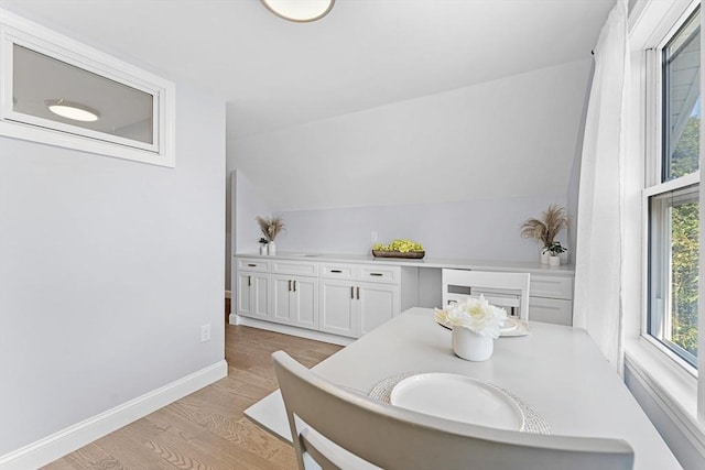 dining space with lofted ceiling, light wood-style flooring, and baseboards