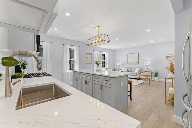 kitchen featuring light stone counters, pendant lighting, recessed lighting, light wood-style flooring, and gray cabinetry