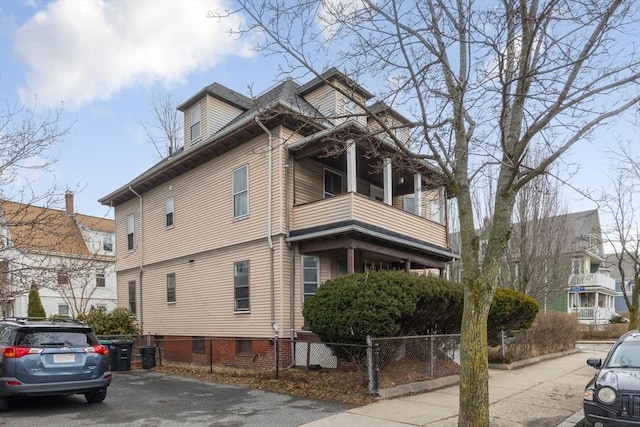 view of property exterior featuring a balcony and a fenced front yard