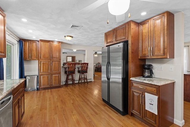 171 Taft Rd, Wilmington, MA 01887 - kitchen with appliances with stainless steel finishes, a ceiling fan, baseboard heating, brown cabinets, and light wood-style flooring