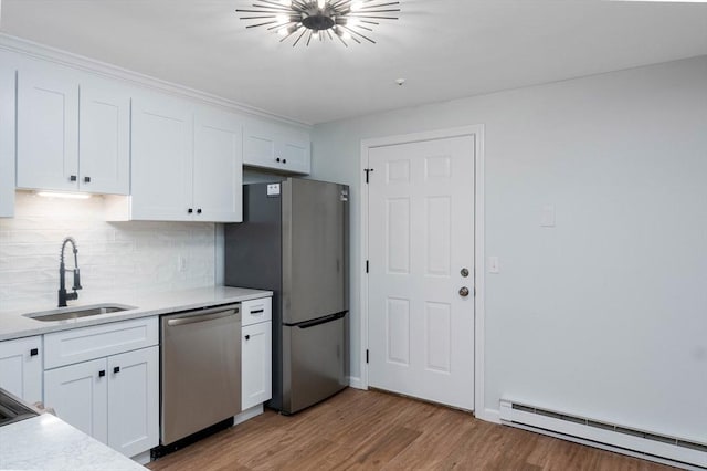 kitchen featuring light wood finished floors, stainless steel appliances, a baseboard radiator, white cabinets, and a sink