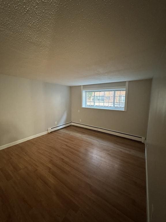 spare room with dark hardwood / wood-style floors, a textured ceiling, and a baseboard radiator