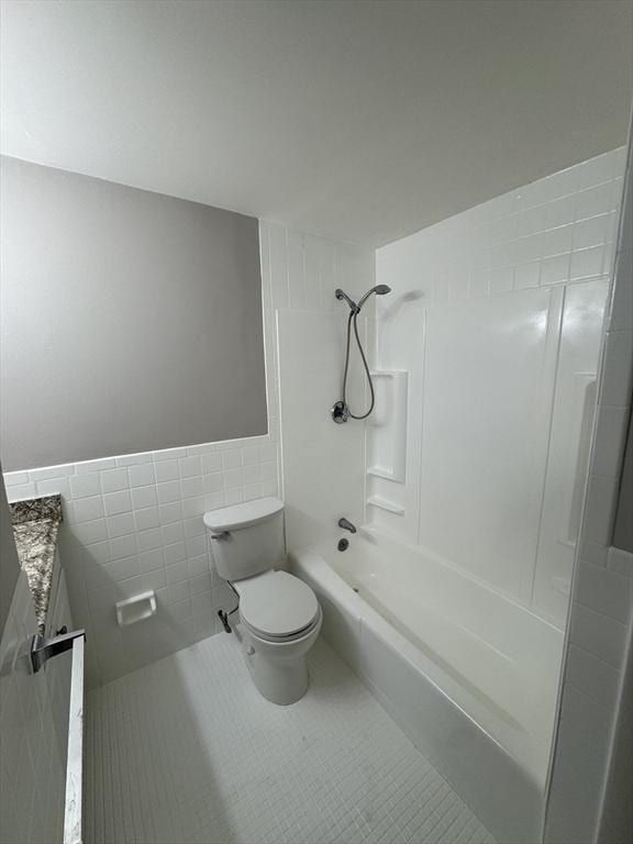 full bathroom with vanity, tile patterned flooring, tiled shower / bath combo, toilet, and tile walls