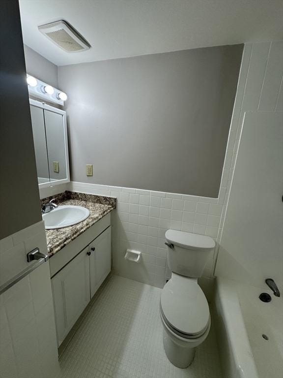 bathroom featuring tile patterned flooring, vanity, toilet, and tile walls