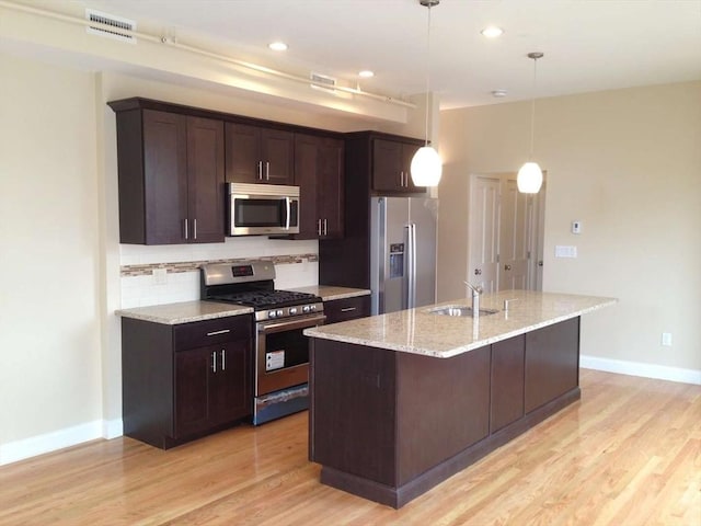 kitchen featuring stainless steel appliances, a sink, dark brown cabinets, baseboards, and light wood-type flooring