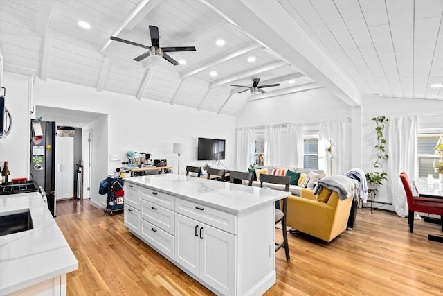 kitchen with a kitchen bar, white cabinetry, a kitchen island, and light stone countertops