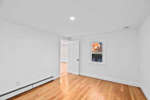 unfurnished room featuring baseboard heating and light hardwood / wood-style flooring