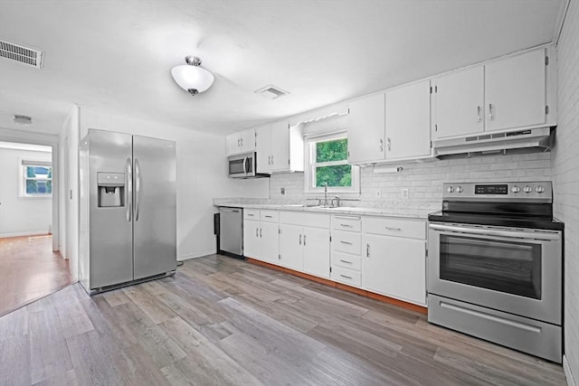 101 Alpha St, Dartmouth, MA 02747 - kitchen featuring appliances with stainless steel finishes, under cabinet range hood, a sink, light countertops, and tasteful backsplash