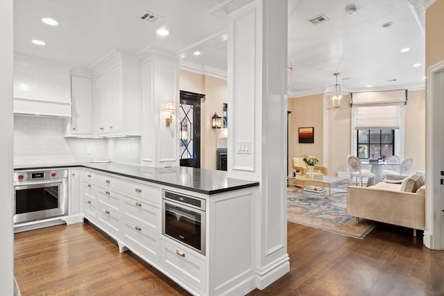 kitchen with oven, visible vents, dark wood-type flooring, and dark countertops