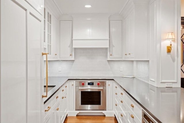 kitchen featuring stainless steel oven, white cabinets, and tasteful backsplash