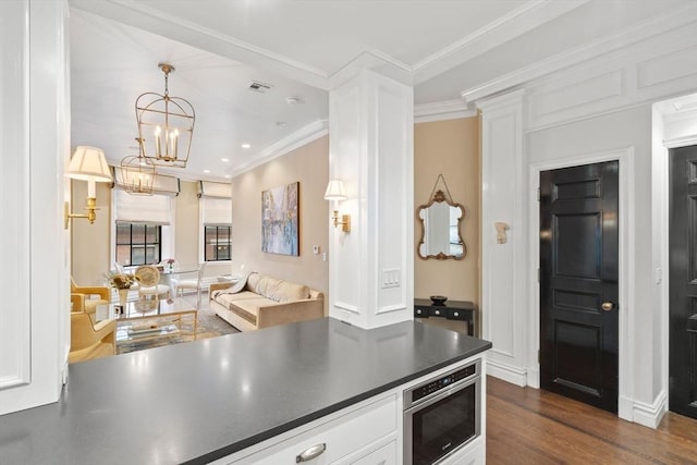 kitchen featuring visible vents, dark countertops, dark wood finished floors, white cabinets, and crown molding