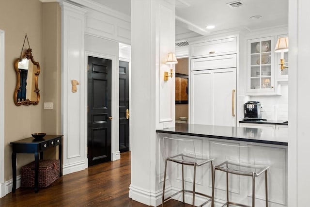 kitchen with dark wood finished floors, dark countertops, glass insert cabinets, and paneled fridge