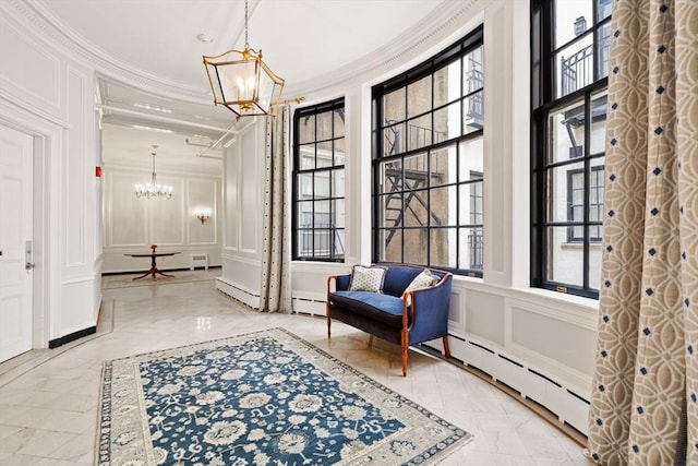 living area featuring crown molding, an inviting chandelier, a decorative wall, marble finish floor, and a baseboard radiator