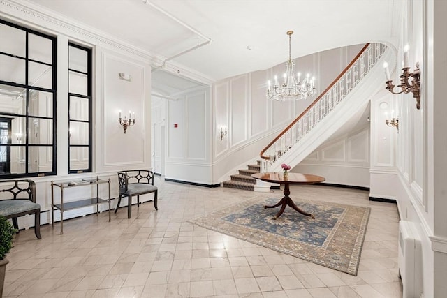 entrance foyer featuring a notable chandelier, a decorative wall, stairway, and baseboard heating