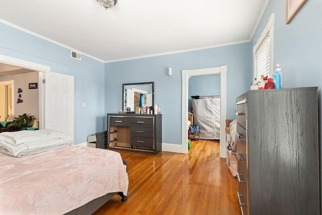 bedroom with ornamental molding, a spacious closet, and hardwood / wood-style floors