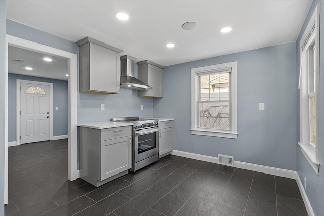 kitchen with gray cabinets, wall chimney range hood, dark tile patterned floors, and stainless steel range with electric stovetop